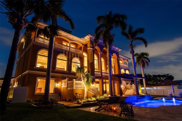 5810 Mariner St, Tampa, FL 33609 - back of house at twilight with stairway, a balcony, fence, a patio, and a pool with connected hot tub