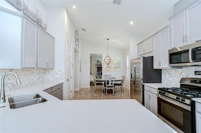 kitchen with stainless steel appliances, a sink, vaulted ceiling, tasteful backsplash, and light countertops