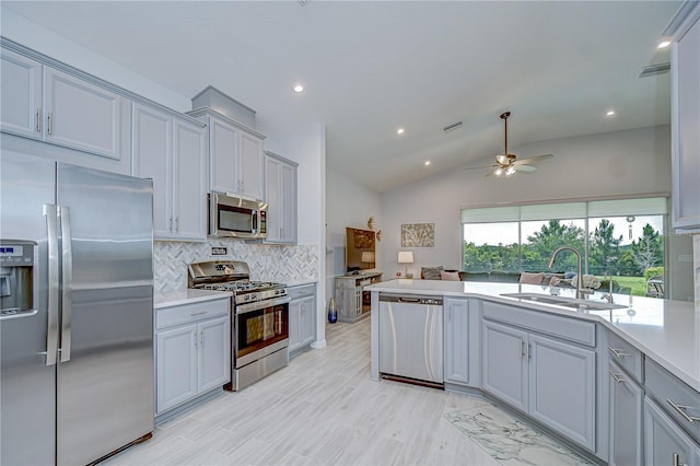 kitchen with stainless steel appliances, a sink, tasteful backsplash, light countertops, and lofted ceiling