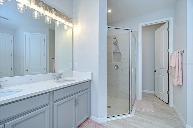 full bath with baseboards, a shower stall, double vanity, and recessed lighting