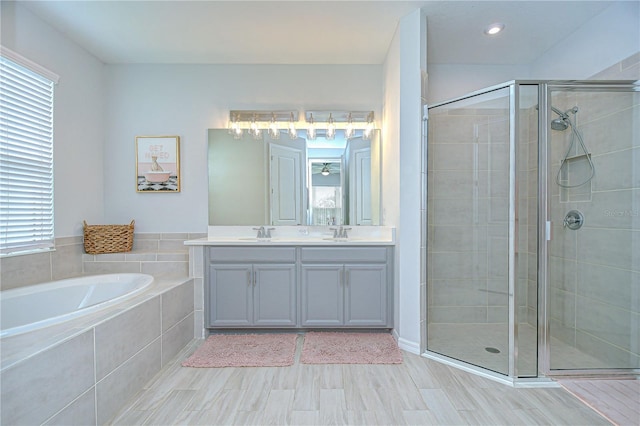 bathroom with a stall shower, a garden tub, double vanity, and wood finished floors