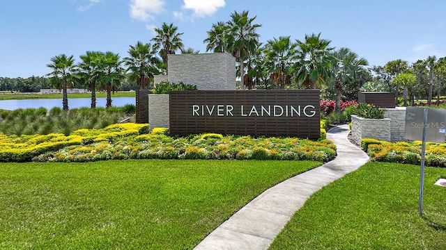 community / neighborhood sign with a yard and a water view