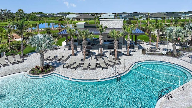 community pool with a patio area, a residential view, and a water view