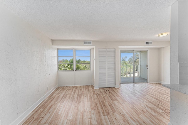 3315 58th Ave S Unit 605, Saint Petersburg, FL 33712 - empty room with light wood-style floors, a textured wall, a textured ceiling, and baseboards