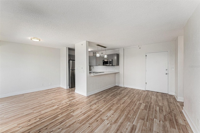 3315 58th Ave S Unit 605, Saint Petersburg, FL 33712 - unfurnished living room featuring light wood-style floors, a textured ceiling, and baseboards