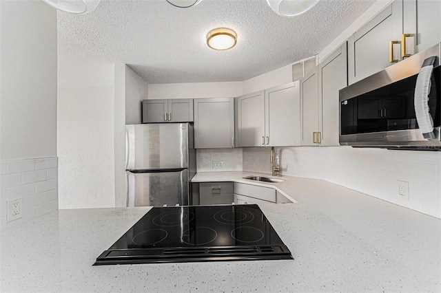 3315 58th Ave S Unit 605, Saint Petersburg, FL 33712 - kitchen with stainless steel appliances, a sink, gray cabinets, decorative backsplash, and a textured ceiling