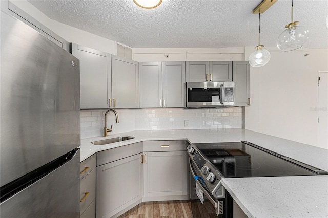 3315 58th Ave S Unit 605, Saint Petersburg, FL 33712 - kitchen featuring stainless steel appliances, gray cabinets, a sink, light wood-type flooring, and a textured ceiling