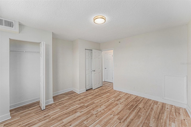 3315 58th Ave S Unit 605, Saint Petersburg, FL 33712 - unfurnished bedroom with light wood finished floors, baseboards, a textured ceiling, and multiple closets