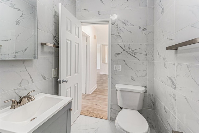 3315 58th Ave S Unit 605, Saint Petersburg, FL 33712 - half bathroom featuring tile walls, marble finish flooring, toilet, and vanity
