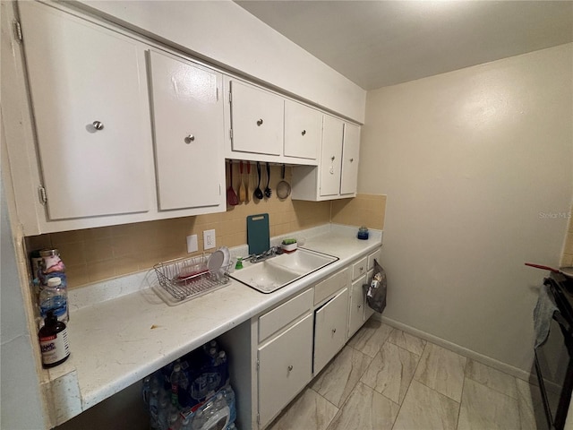 5901 E Gibson Ave, Tampa, FL 33617 - kitchen featuring a sink, light countertops, white cabinets, tasteful backsplash, and light marble finish flooring