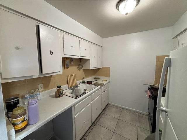 5901 E Gibson Ave, Tampa, FL 33617 - kitchen featuring freestanding refrigerator, a sink, light countertops, white cabinetry, and light tile patterned floors