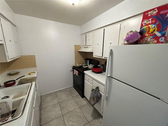 5901 E Gibson Ave, Tampa, FL 33617 - kitchen with freestanding refrigerator, black / electric stove, under cabinet range hood, decorative backsplash, and white cabinetry
