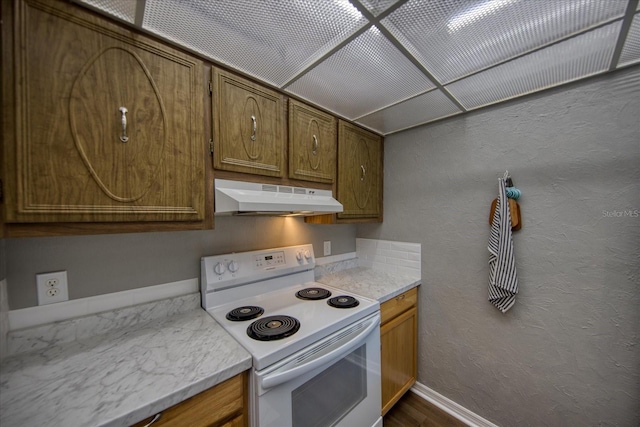 kitchen with under cabinet range hood, white electric range, light countertops, and brown cabinets