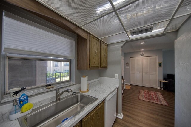 kitchen featuring a sink, dark wood-type flooring, dishwasher, light countertops, and brown cabinets