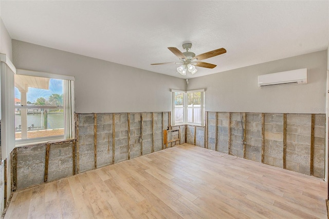 365 La Hacienda Dr, Indian Rocks Beach, FL 33785 - empty room featuring a wall unit AC, wood finished floors, and a ceiling fan