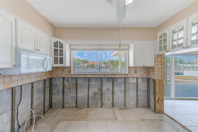 365 La Hacienda Dr, Indian Rocks Beach, FL 33785 - kitchen featuring white microwave, white cabinets, glass insert cabinets, and healthy amount of natural light