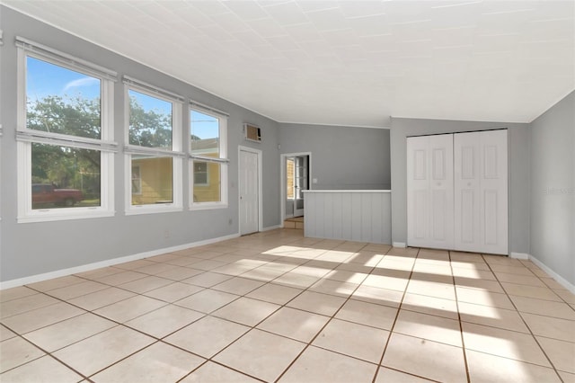 unfurnished living room with light tile patterned floors, baseboards, and a wall mounted AC