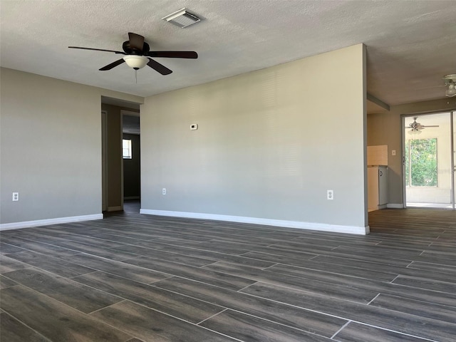 unfurnished room with a ceiling fan, dark wood-style flooring, baseboards, and a textured ceiling