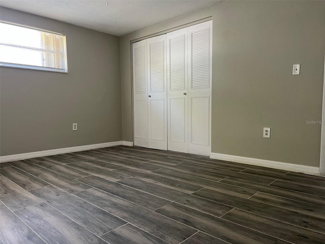 unfurnished bedroom featuring dark wood finished floors, a closet, baseboards, and a textured ceiling