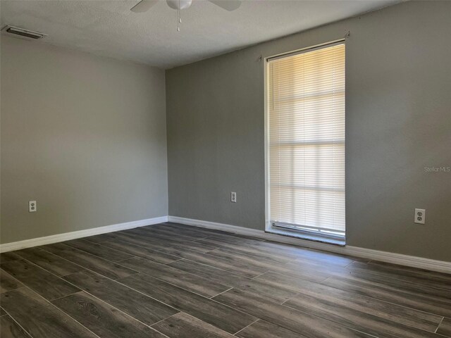 empty room with a ceiling fan, dark wood-style floors, and baseboards