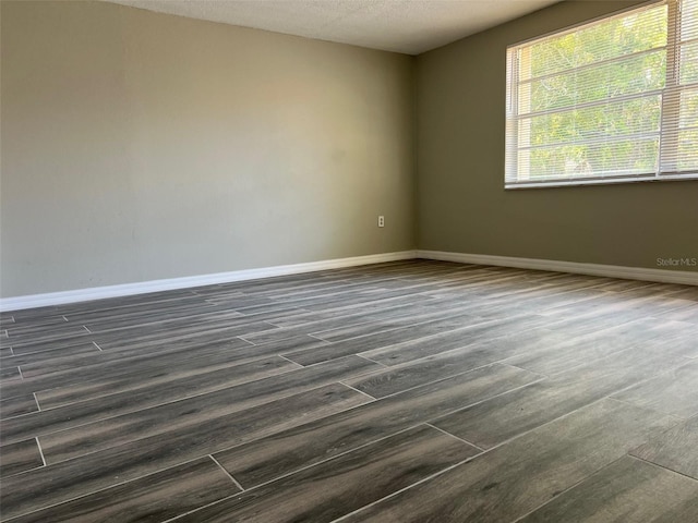spare room with dark wood finished floors, baseboards, and a textured ceiling