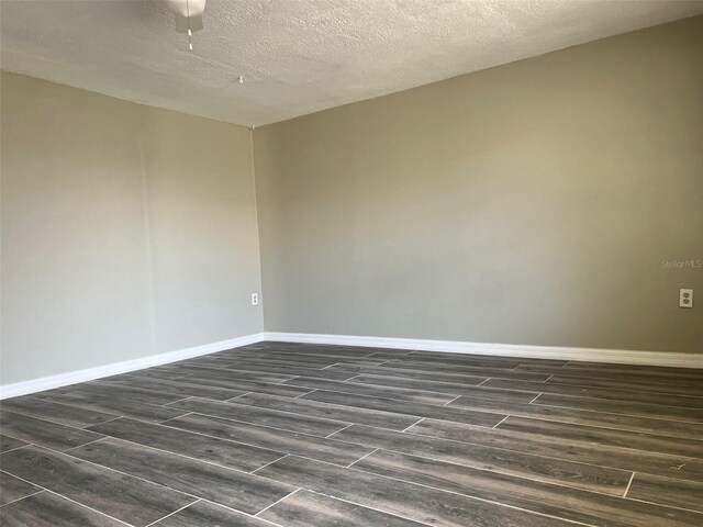 spare room with dark wood-style floors, baseboards, and a textured ceiling