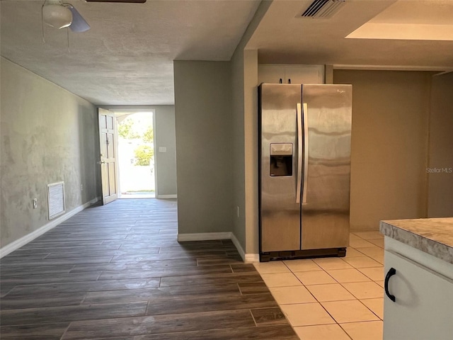 kitchen featuring stainless steel fridge with ice dispenser, a ceiling fan, light wood-style floors, and baseboards