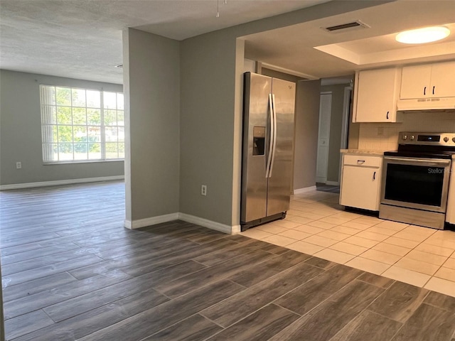 kitchen with appliances with stainless steel finishes, under cabinet range hood, baseboards, wood finish floors, and white cabinets