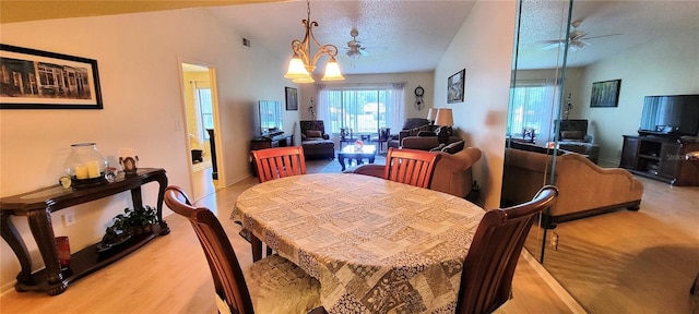 dining area featuring ceiling fan, a chandelier, light wood-type flooring, and lofted ceiling