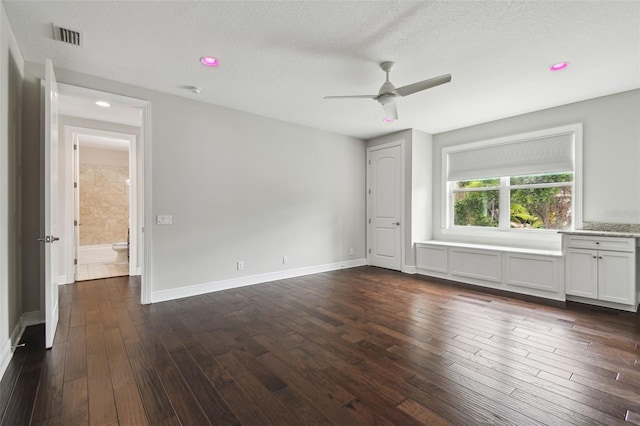 unfurnished bedroom with dark wood-type flooring, a textured ceiling, baseboards, and ceiling fan