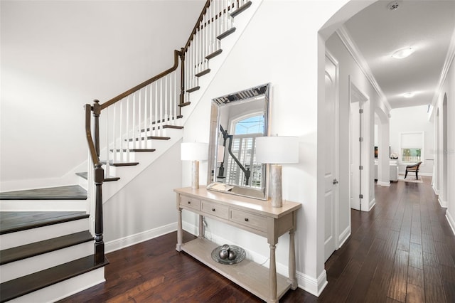 stairs featuring arched walkways, hardwood / wood-style flooring, baseboards, and ornamental molding