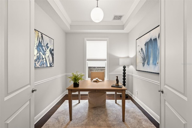 office space featuring dark wood-style flooring, a tray ceiling, ornamental molding, and baseboards