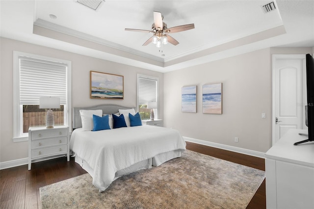 bedroom featuring a raised ceiling, ornamental molding, baseboards, and dark wood-style floors