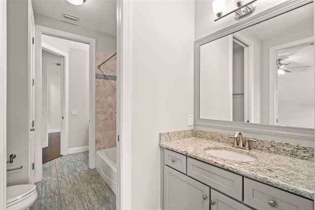 full bathroom with ceiling fan, vanity, toilet, shower / bath combination, and baseboards