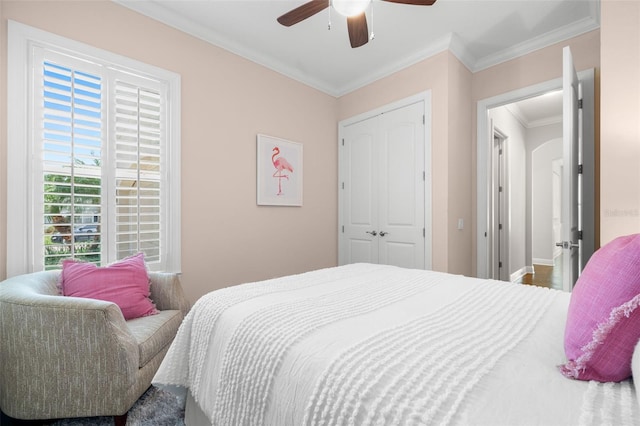 bedroom featuring crown molding, ceiling fan, a closet, and baseboards