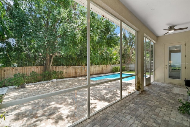 unfurnished sunroom with ceiling fan and brick patterned floors