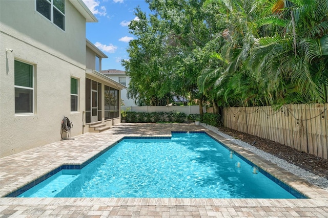 view of pool featuring a sunroom, a fenced backyard, and a patio