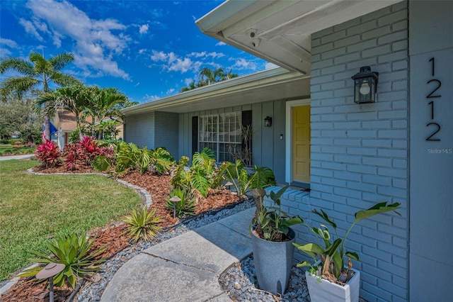 property entrance featuring brick siding, a lawn, and board and batten siding