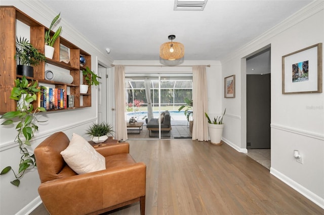 living area featuring wood finished floors, ornamental molding, and baseboards