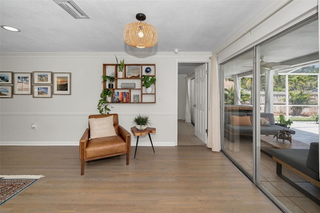 living area featuring ornamental molding, wood finished floors, and baseboards