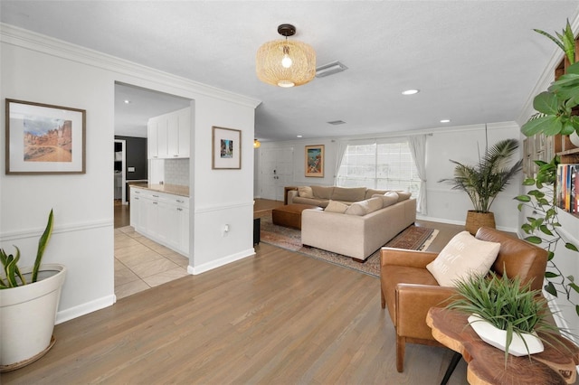 living area with crown molding, light wood-type flooring, recessed lighting, and baseboards