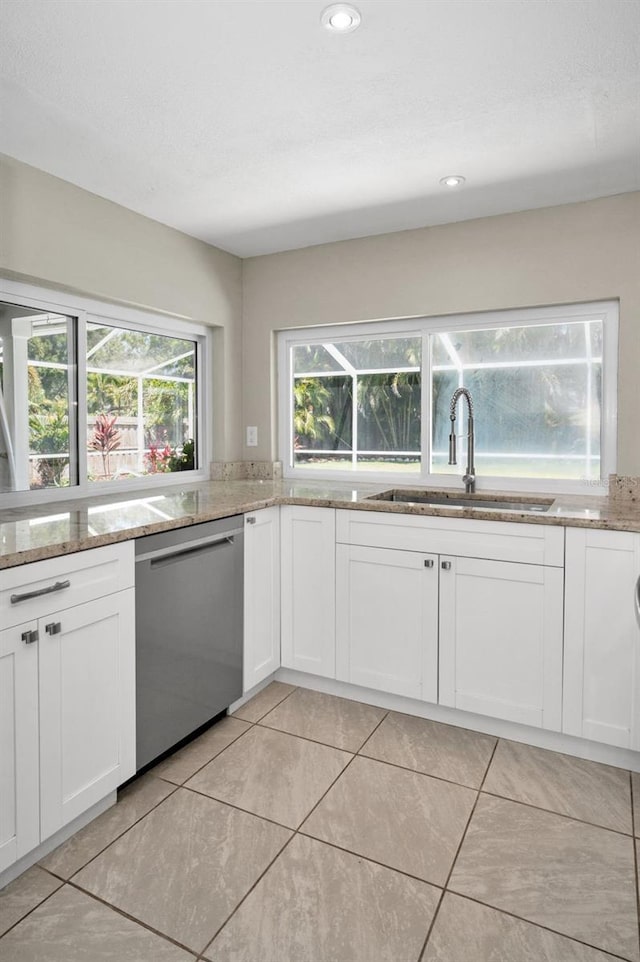 kitchen with stainless steel dishwasher, a sink, light stone counters, white cabinets, and recessed lighting