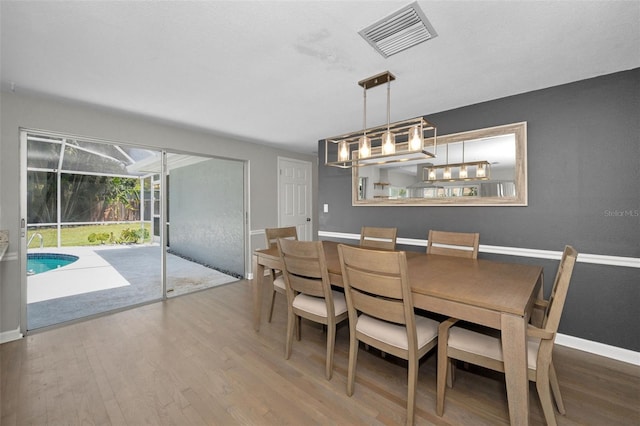 dining room featuring wood finished floors, baseboards, and a sunroom
