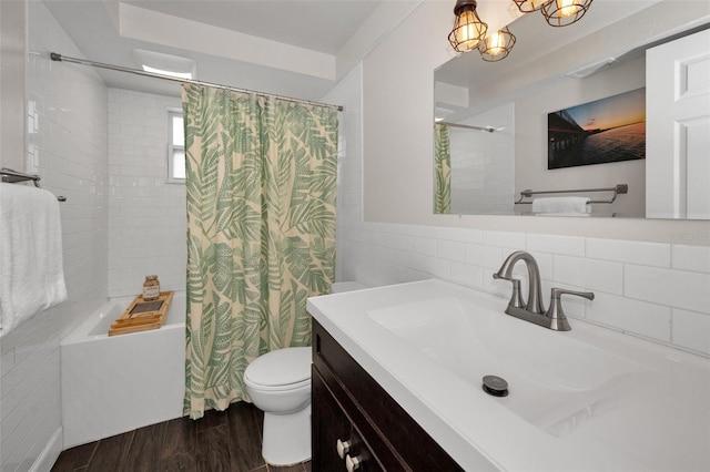 bathroom featuring shower / tub combo with curtain, wood finished floors, vanity, toilet, and a chandelier