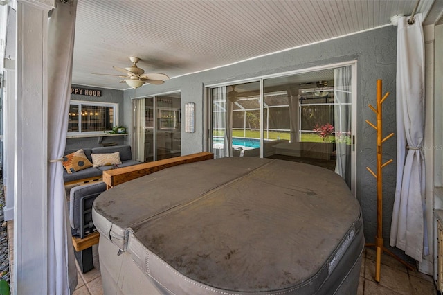 bedroom featuring a textured wall, a ceiling fan, a sunroom, and access to outside
