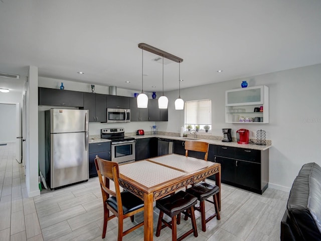 106 E Cedar St, Tarpon Springs, FL 34689 - kitchen featuring appliances with stainless steel finishes, light countertops, a sink, dark cabinets, and decorative light fixtures