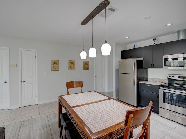 106 E Cedar St, Tarpon Springs, FL 34689 - kitchen featuring stainless steel appliances, dark cabinets, light countertops, hanging light fixtures, and wood tiled floors