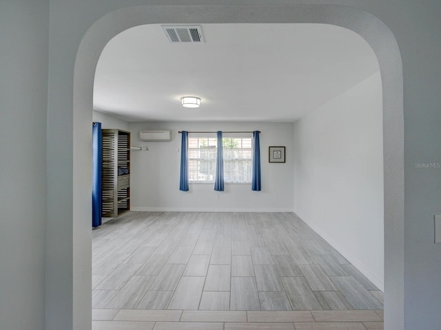 106 E Cedar St, Tarpon Springs, FL 34689 - empty room featuring a wall mounted AC, arched walkways, baseboards, and wood finished floors
