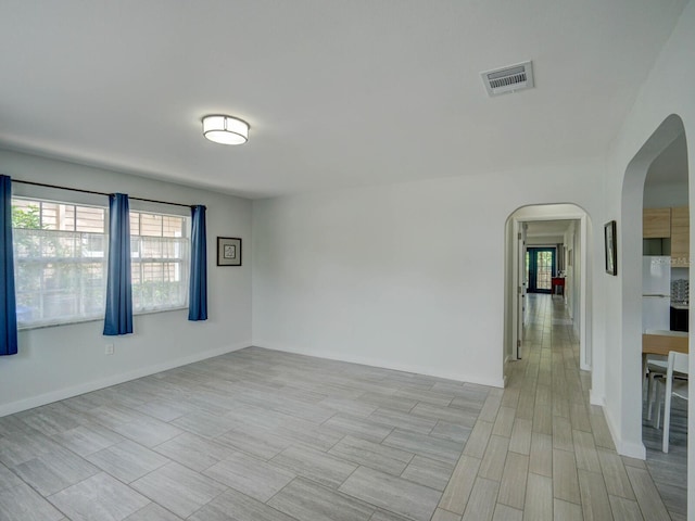 106 E Cedar St, Tarpon Springs, FL 34689 - empty room featuring arched walkways, healthy amount of natural light, baseboards, and light wood-style flooring