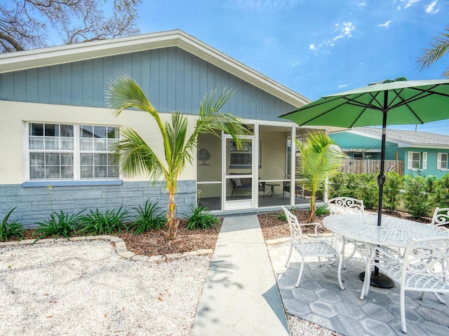 106 E Cedar St, Tarpon Springs, FL 34689 - doorway to property featuring a patio, stone siding, fence, and outdoor dining space